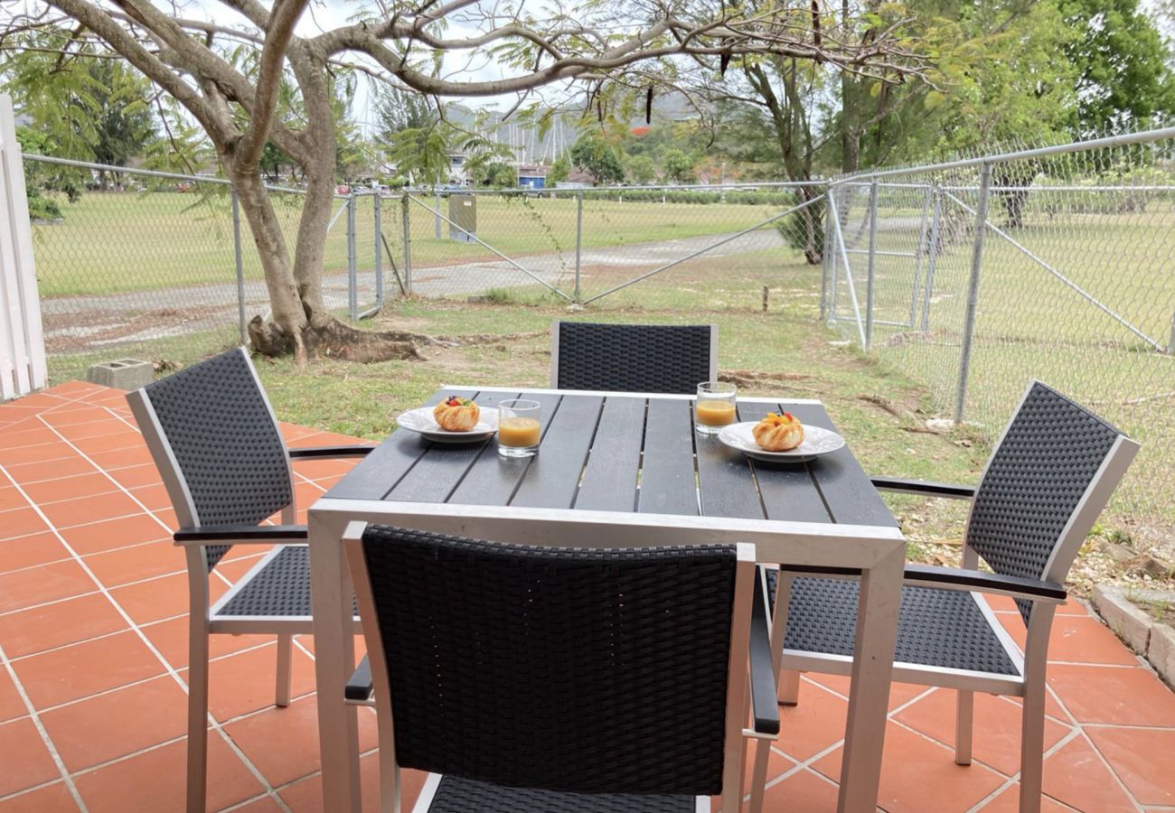 Garden-view outdoor terrace furnished with a barbeque, dining table and chairs at Jolly Harbour Villa Rentals